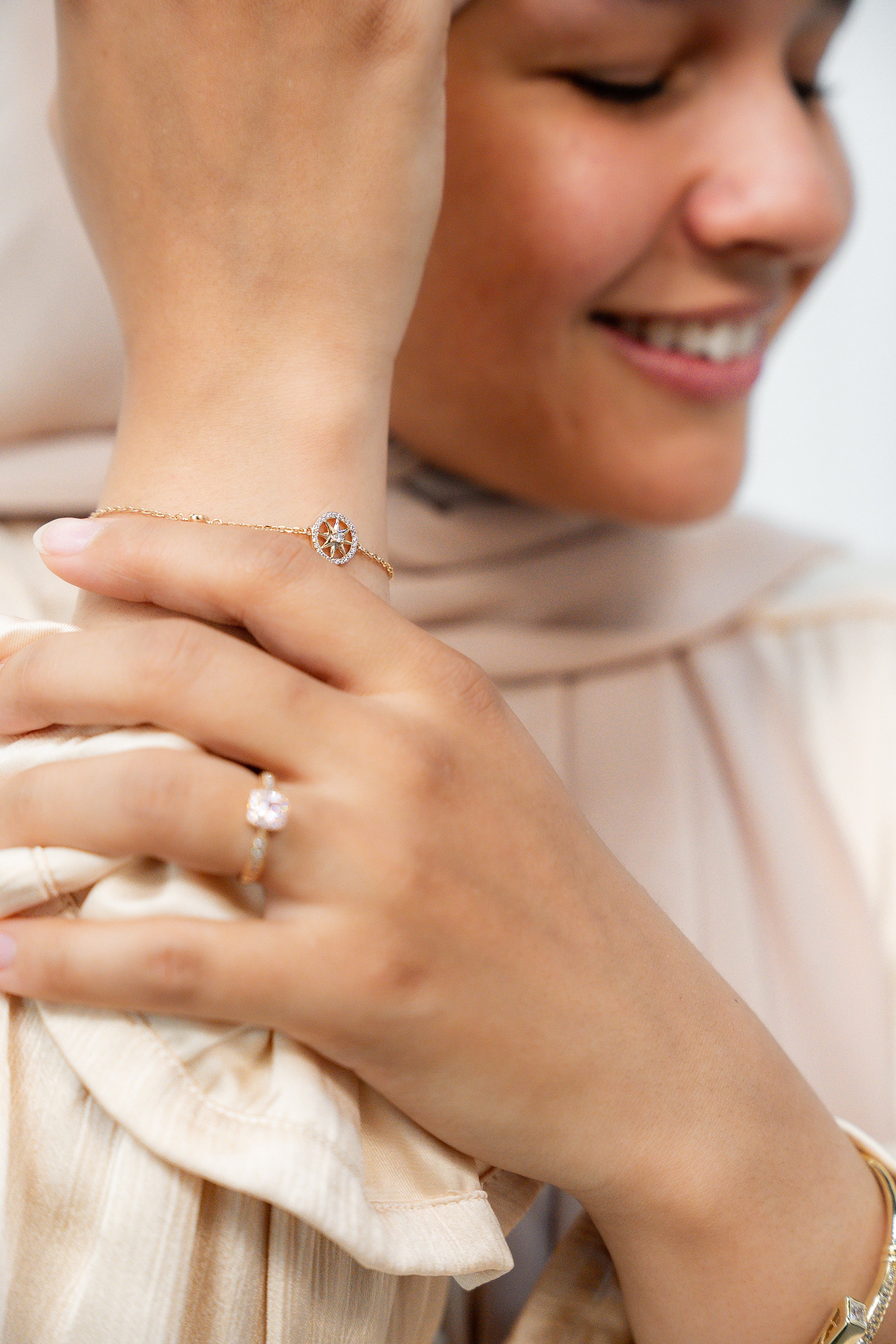 Woman wearing a ring and bracelet, with a blurred background. Harma Jewelry gold plated Find Your Way Compass Bracelet