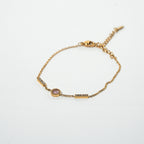 Gold bracelet with a small pink gemstone on a light gray background. Harma Jewelry gold plated I Am Healing PINK Zirconia Bracelet