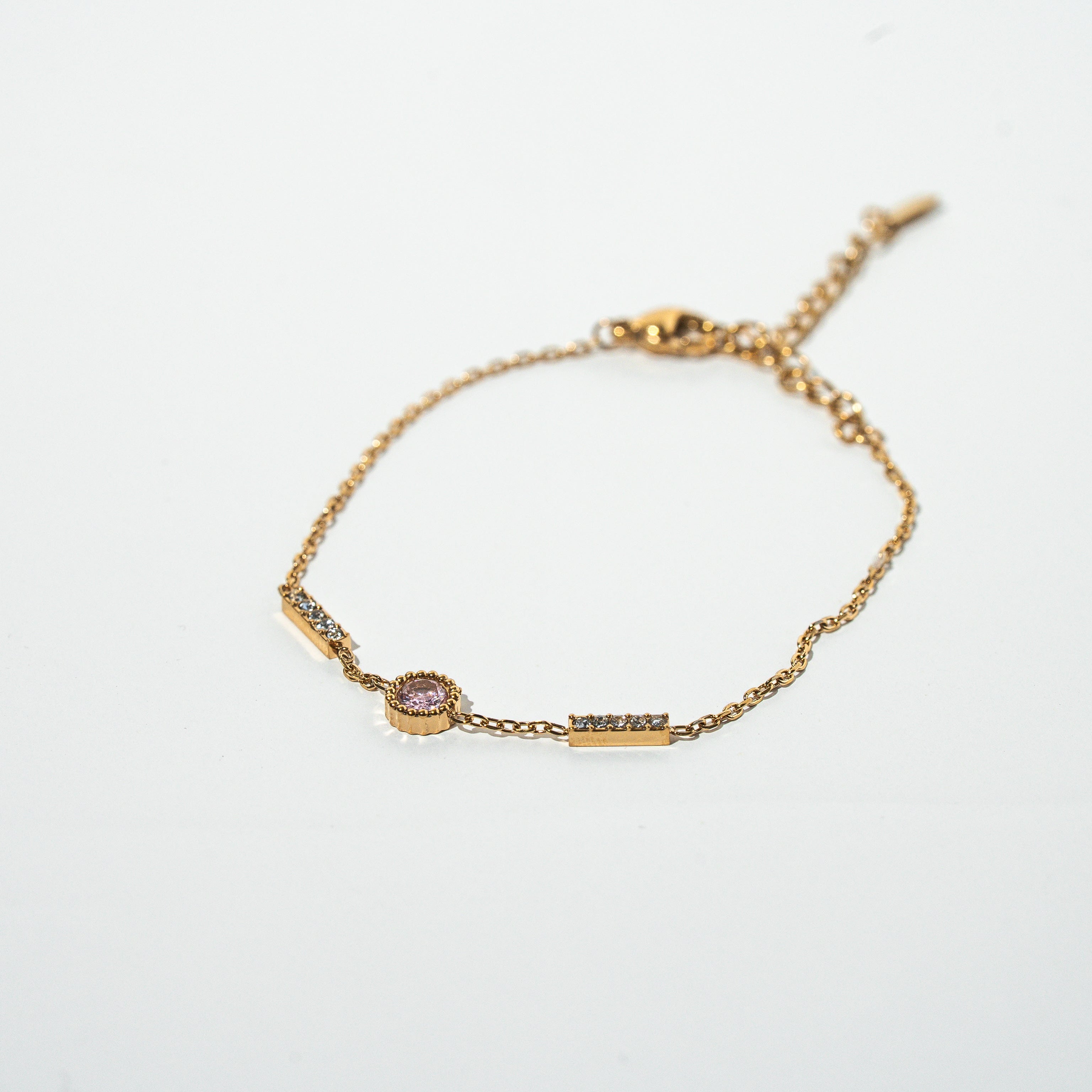 Gold bracelet with a small pink gemstone on a light gray background. Harma Jewelry gold plated I Am Healing PINK Zirconia Bracelet