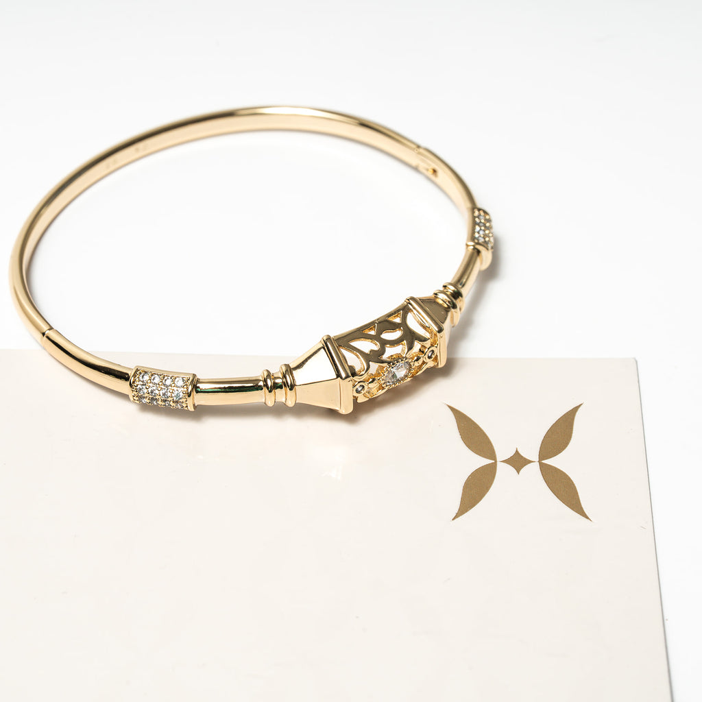 Gold bracelet with decorative elements on a white card with a butterfly design. Harma Luminous Noor Lantern Bracelet