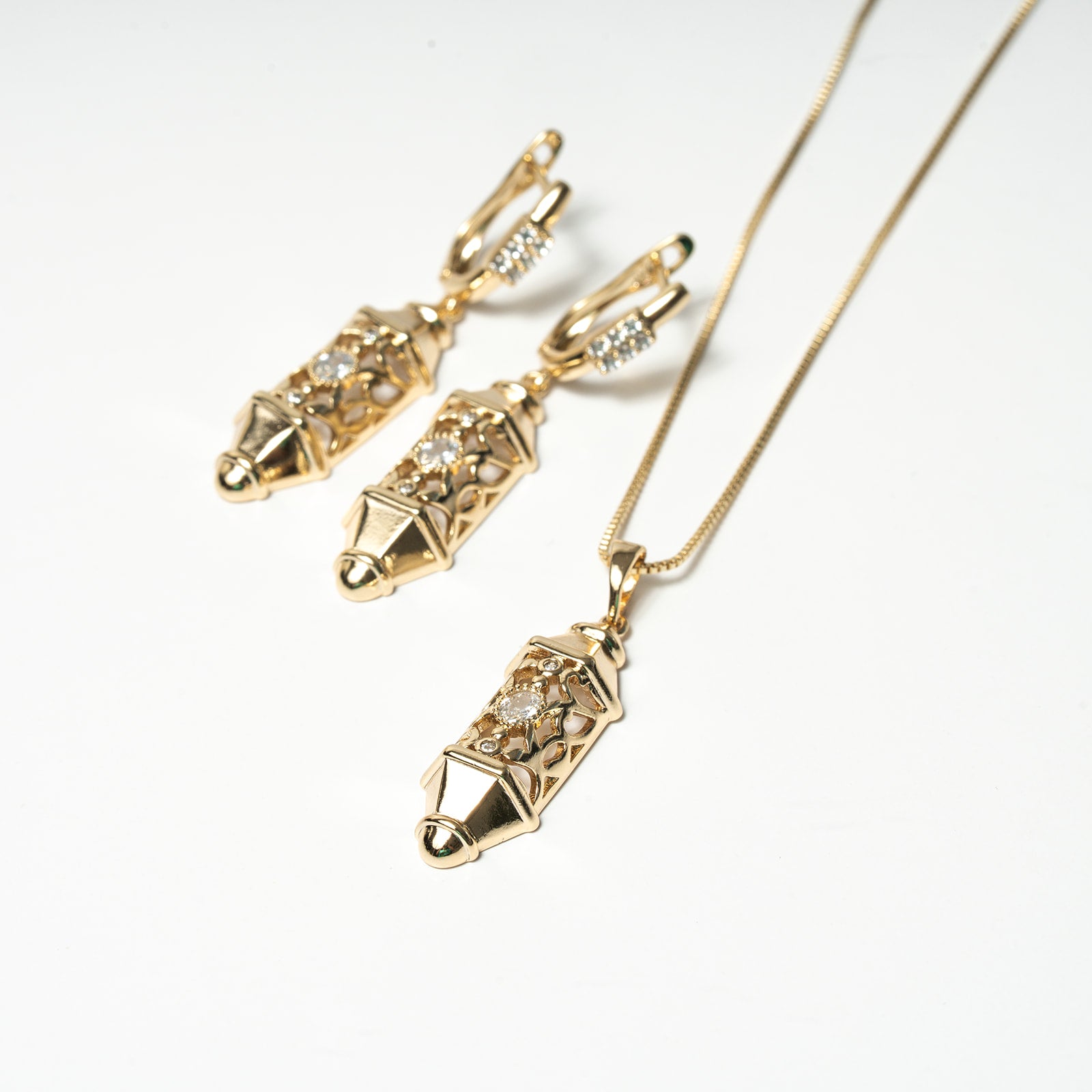 Gold jewelry set with earrings and necklace on a white background Harma Luminous Noor Lantern Necklace Set
