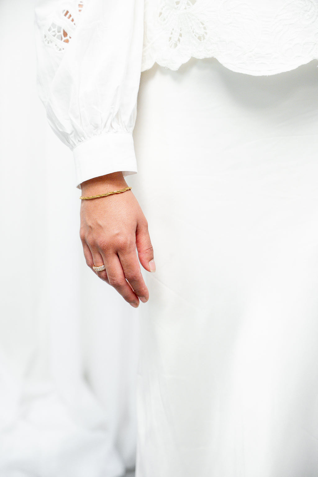 Close-up of a hand wearing a gold ring on a white background