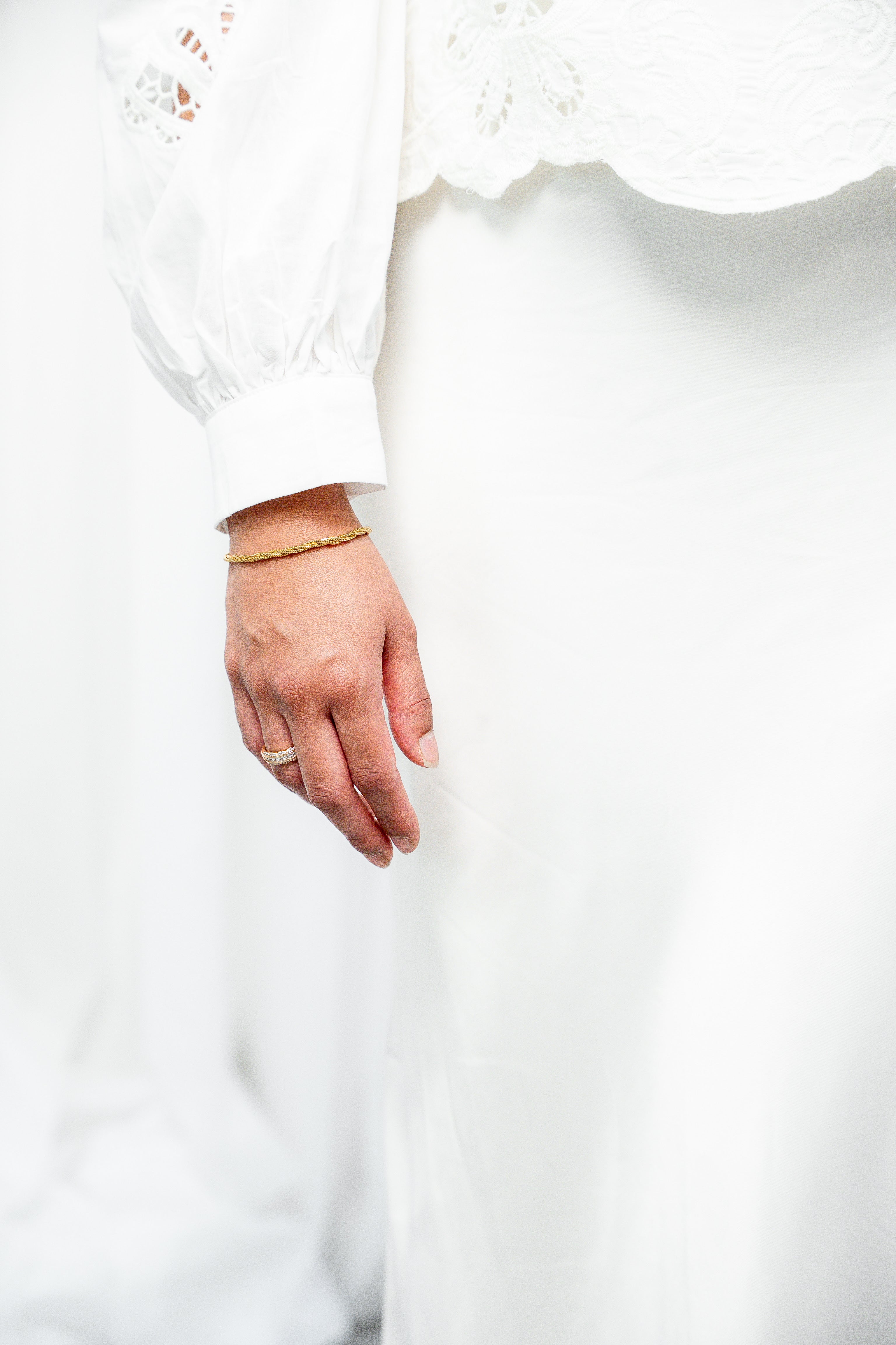 Close-up of a hand wearing a gold ring on a white background