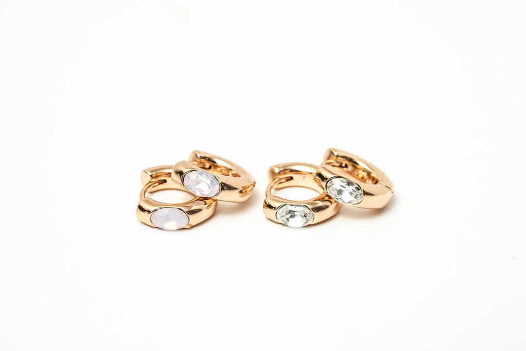 Pair of rose gold hoop earrings with clear gemstones on a white background