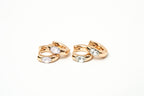 Pair of rose gold hoop earrings with clear gemstones on a white background