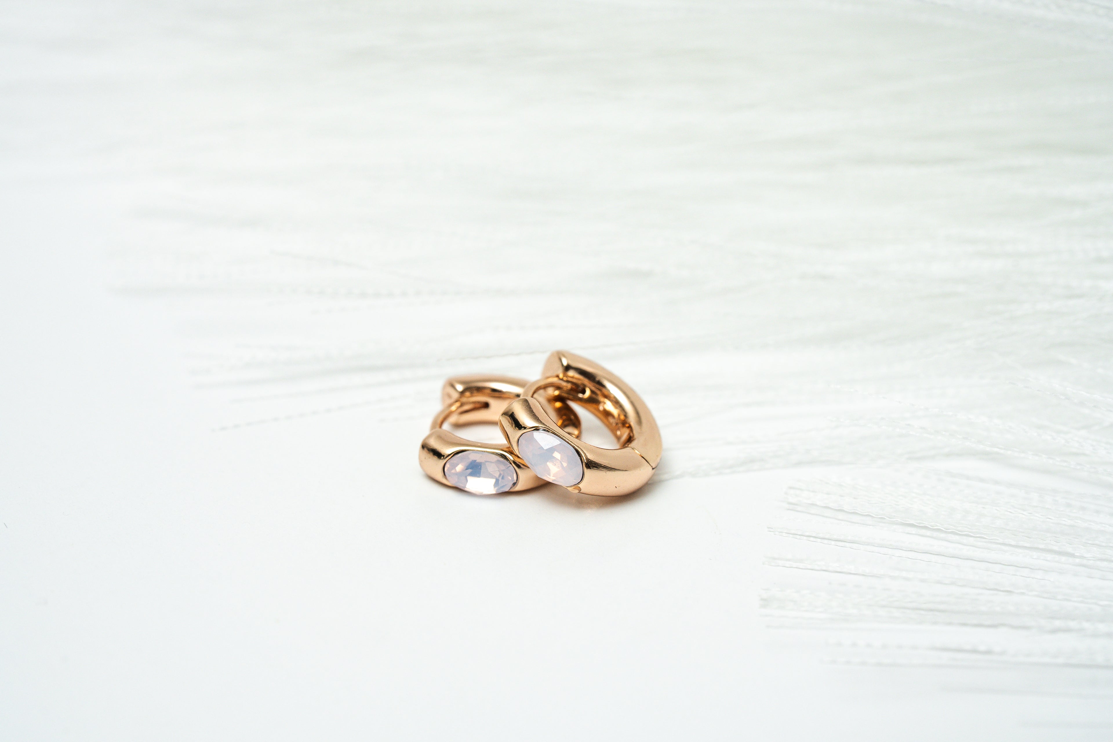 Gold ring with two circular stones on a light background