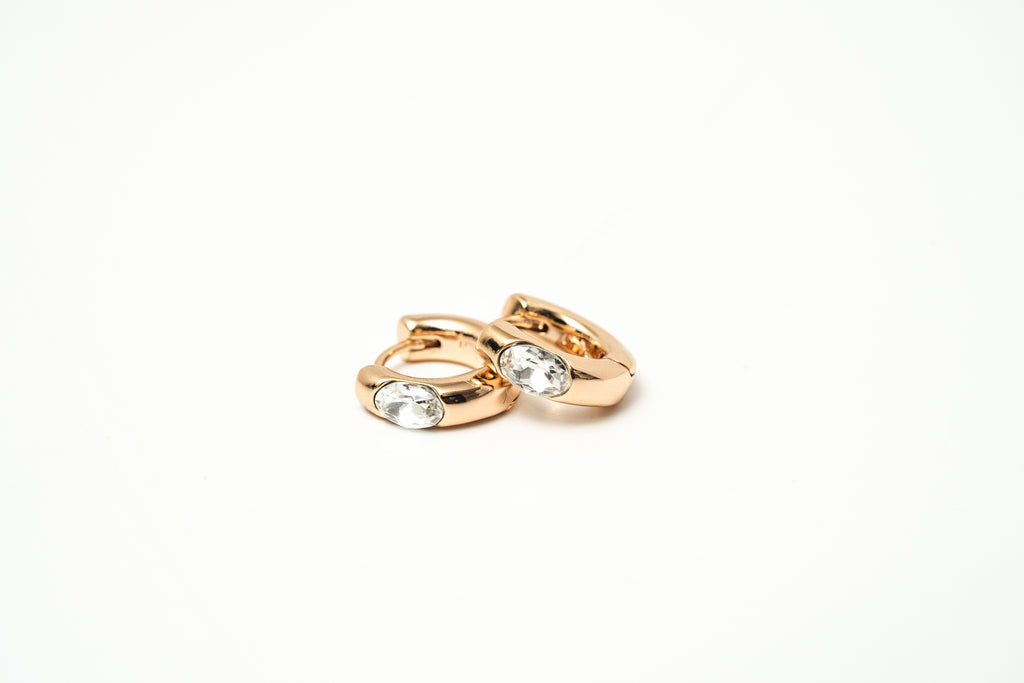 Pair of rose gold hoop earrings with clear gemstones on a white background