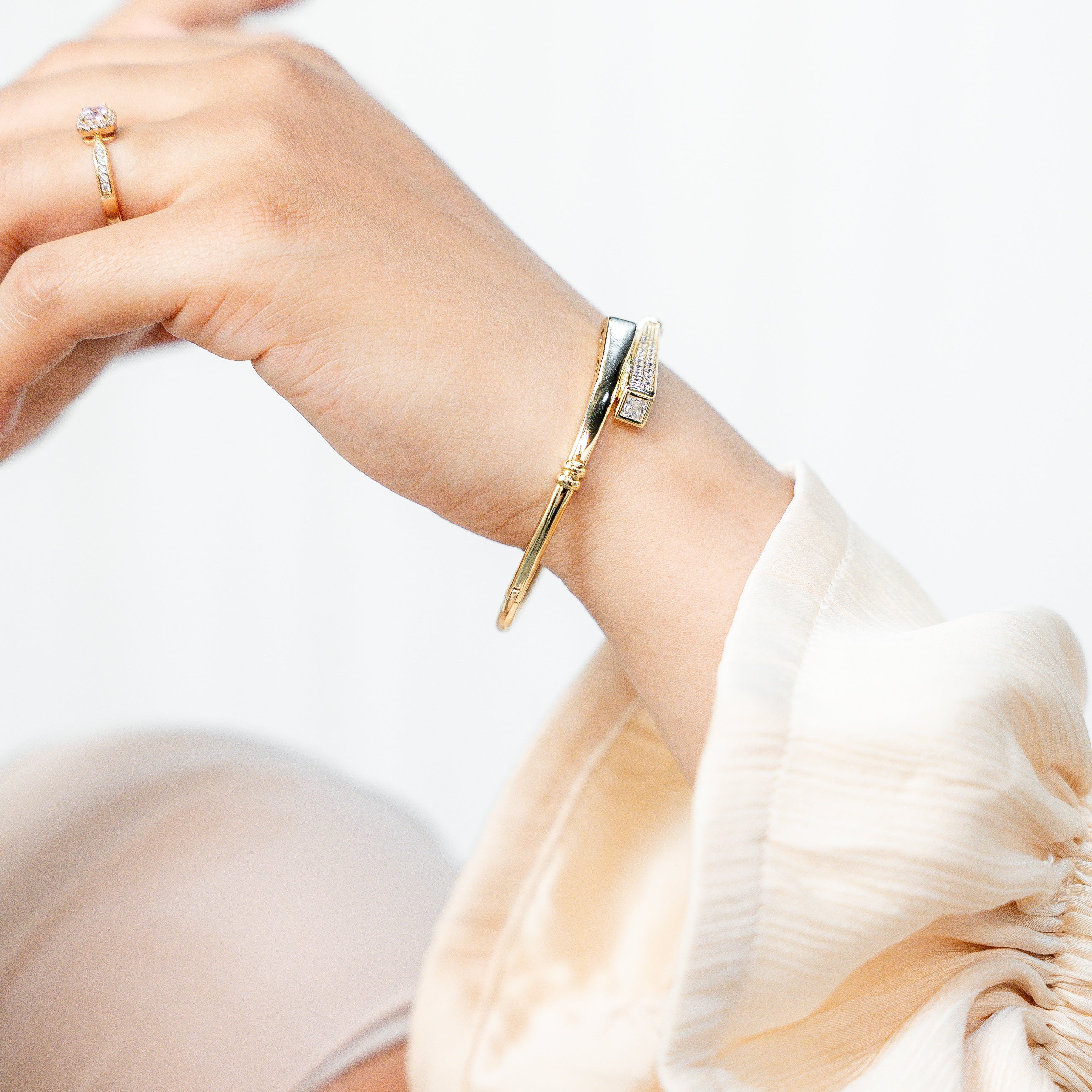 Close-up of a hand wearing a gold bracelet on a plain background. Harma jewelry Gold plated I Am Whole Again Bangle Bracelet
