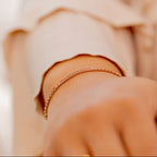 Close-up of a hand wearing a gold bracelet on a blurred background Harma jewelry gold plated I Am Becoming PINK Link Bracelet