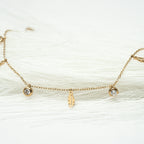 Gold bracelet with small charms on a white background. Harma jewelry gold plated I Am Light Feather Bracelet