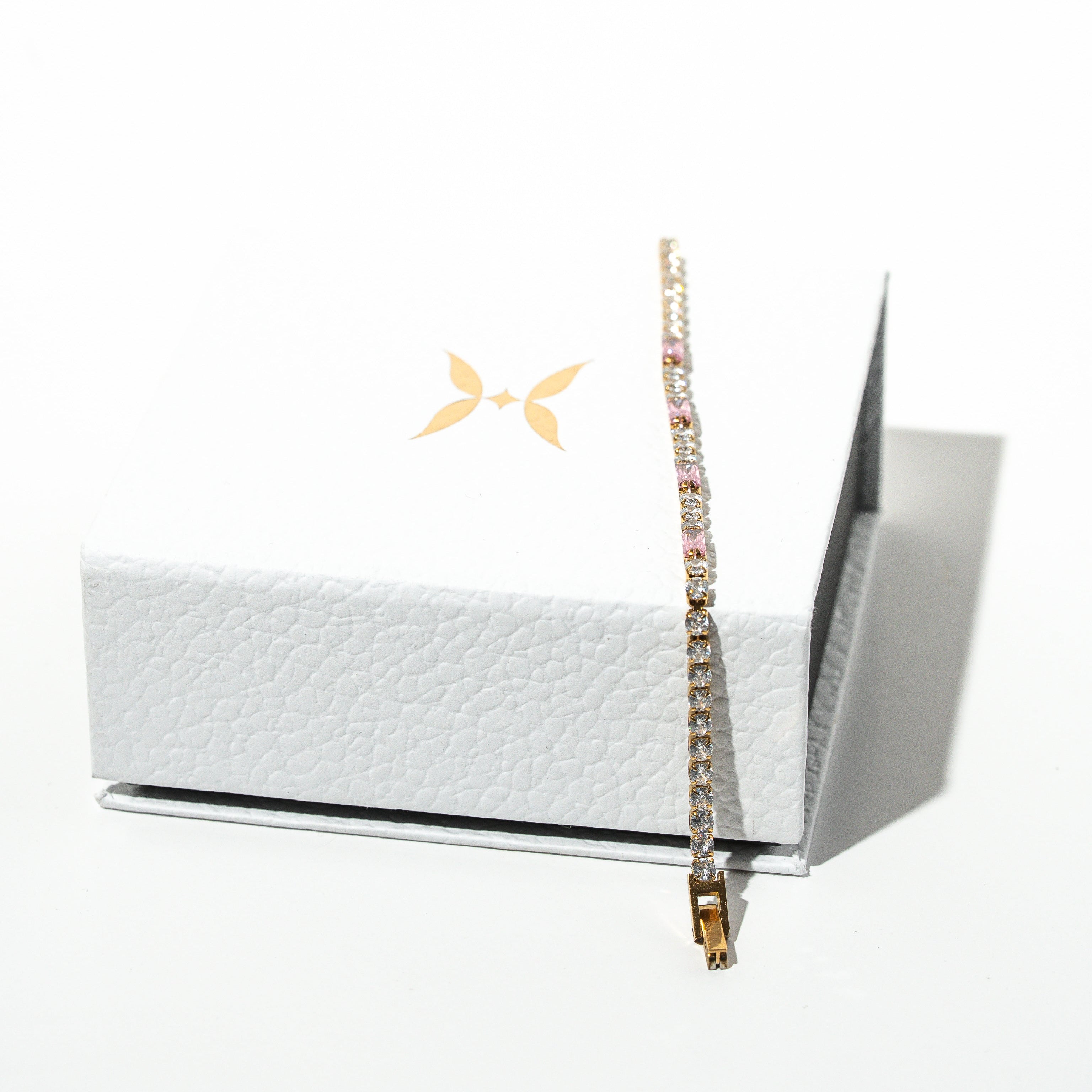 Bracelet displayed on a white box with a brand logo in the corner. Harma jewelry gold plated Moments of PINK Tennis Bracelet