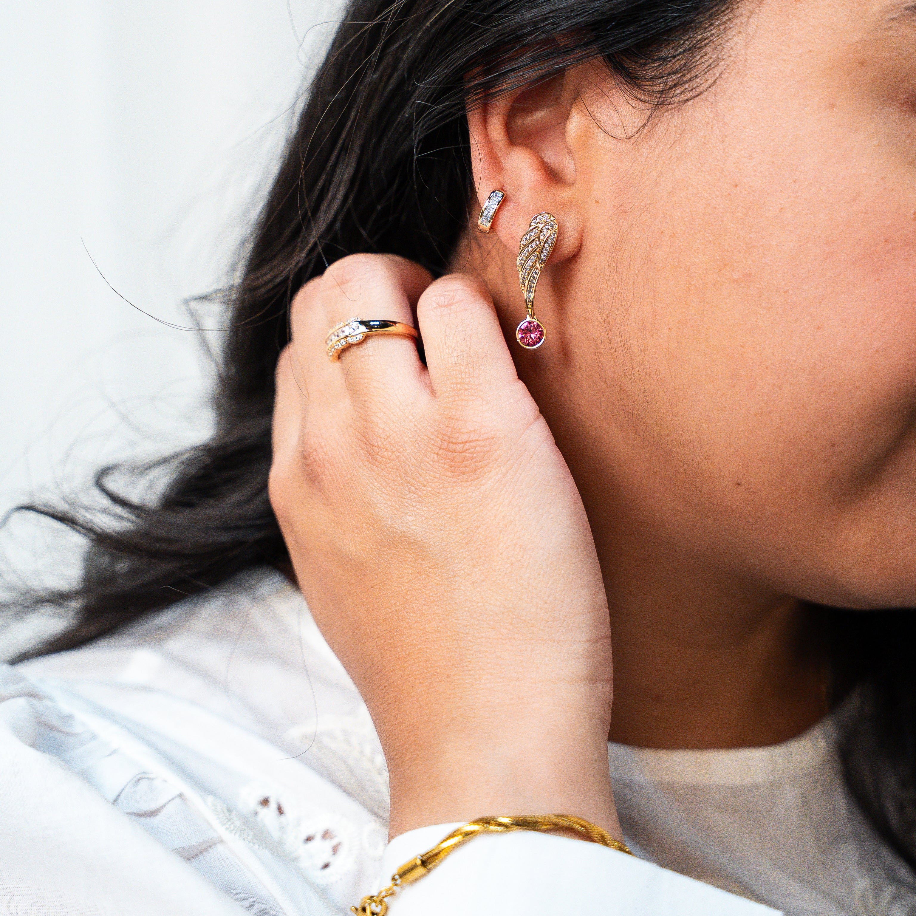 Person wearing earrings and a ring, with a plain background. Rise Again Crystal Wings Earrings