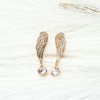 Rose gold angel wing earrings with clear gemstones on a light background