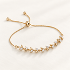A delicate gold adjustable chain bracelet featuring a row of small leaf-shaped settings set with clear stones, displayed on a clean white background. Whispering Magnolia Marquise Adjustable Bracelet 18k gold plated Harma Jewelry