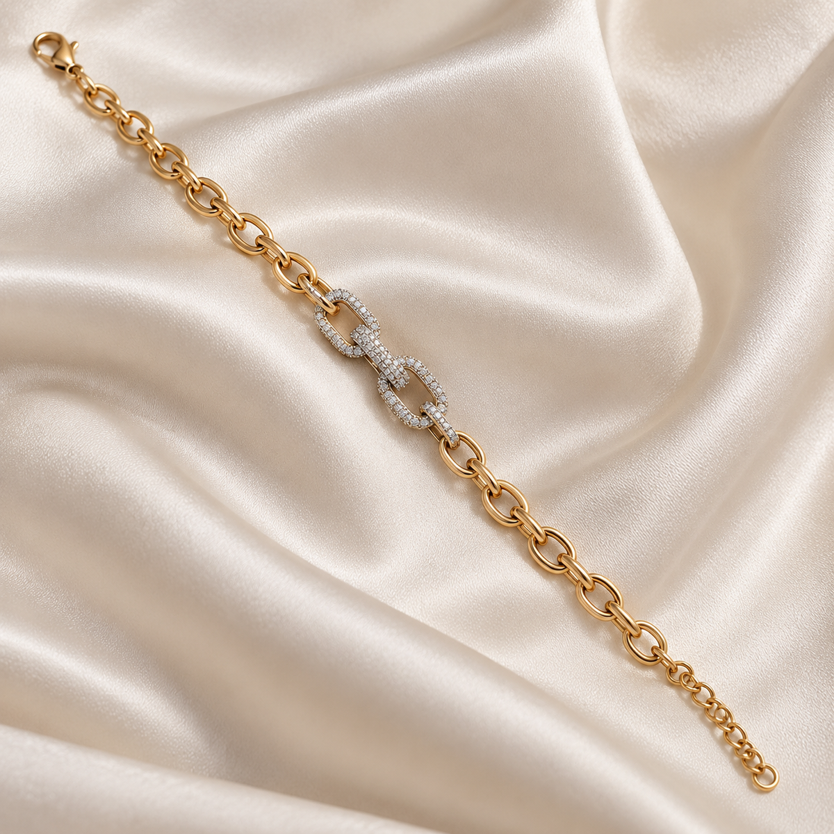 A gold chain bracelet with a central interlocking double-O charm paved with clear stones, displayed on a draped cream satin fabric background. lan_Pave_Link_Zirconia_Bracelet_18k_gold_plated_harma_jewelry_1